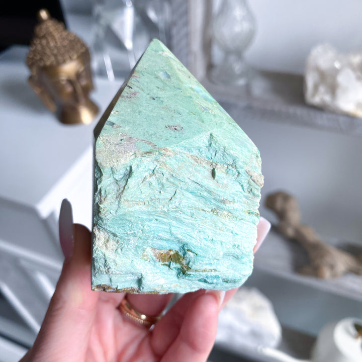 Turquoise crystal held in a hand with a blurred background