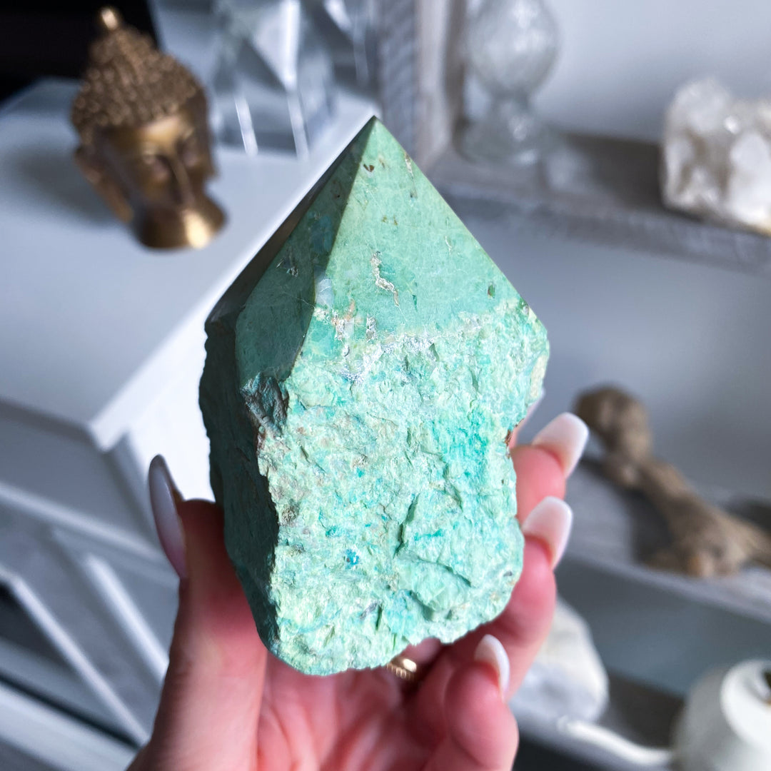Turquoise crystal held in a hand with a blurred background