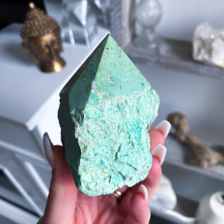 Turquoise crystal held in a hand with a blurred background