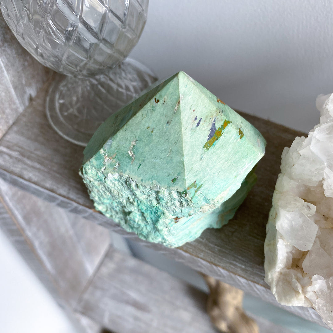 Green crystal on a wooden surface with a white background
