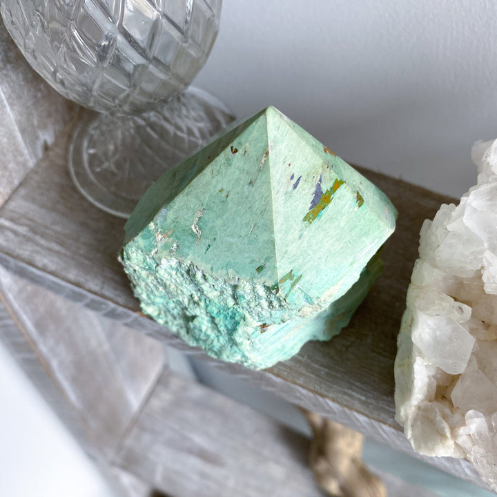 Green crystal on a wooden surface with a white background