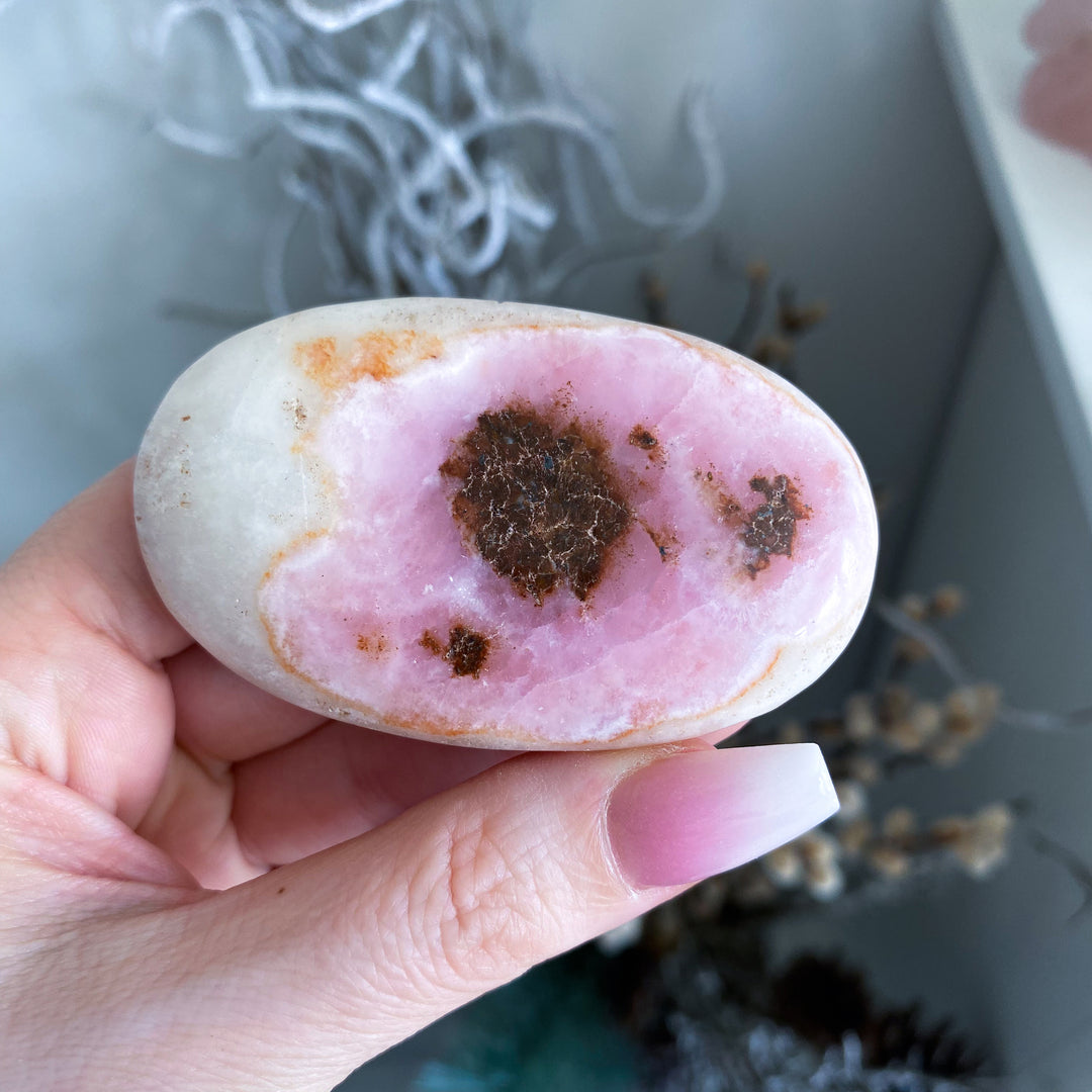 Hand holding a pink and brown stone with a blurred background