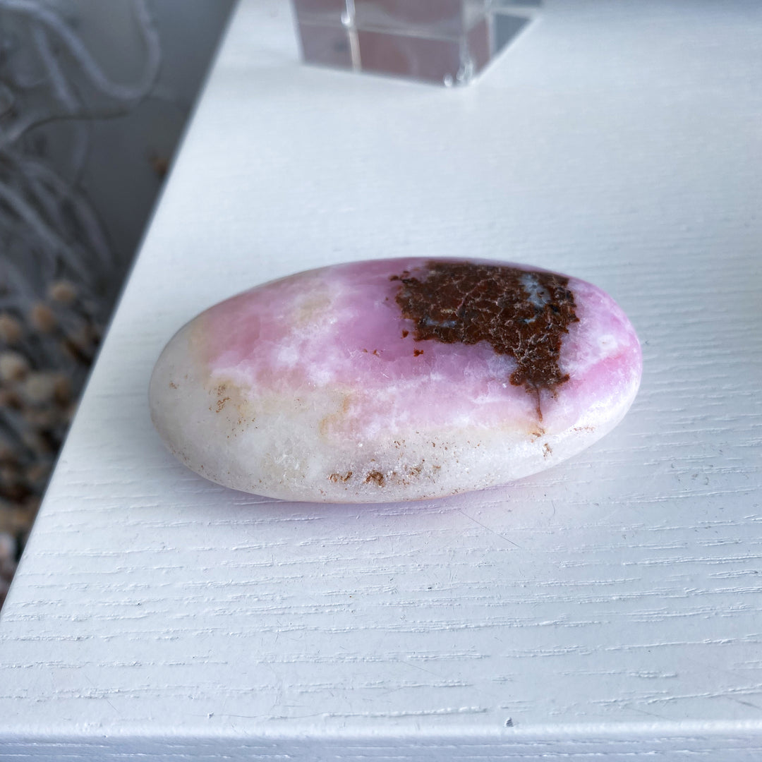 Pink and white stone with brown center on a light gray surface