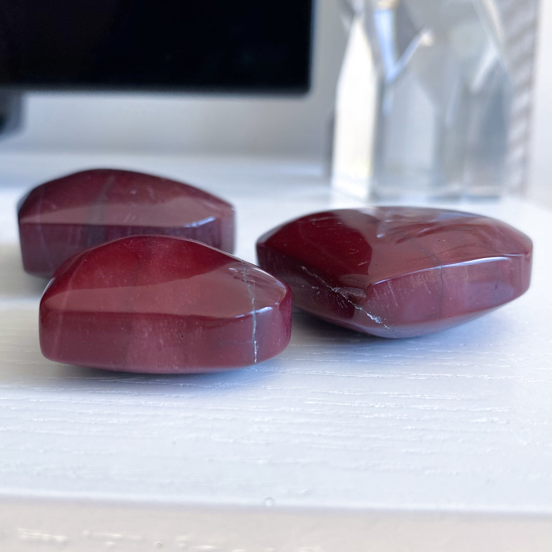 Three red stones on a white surface with a blurred background