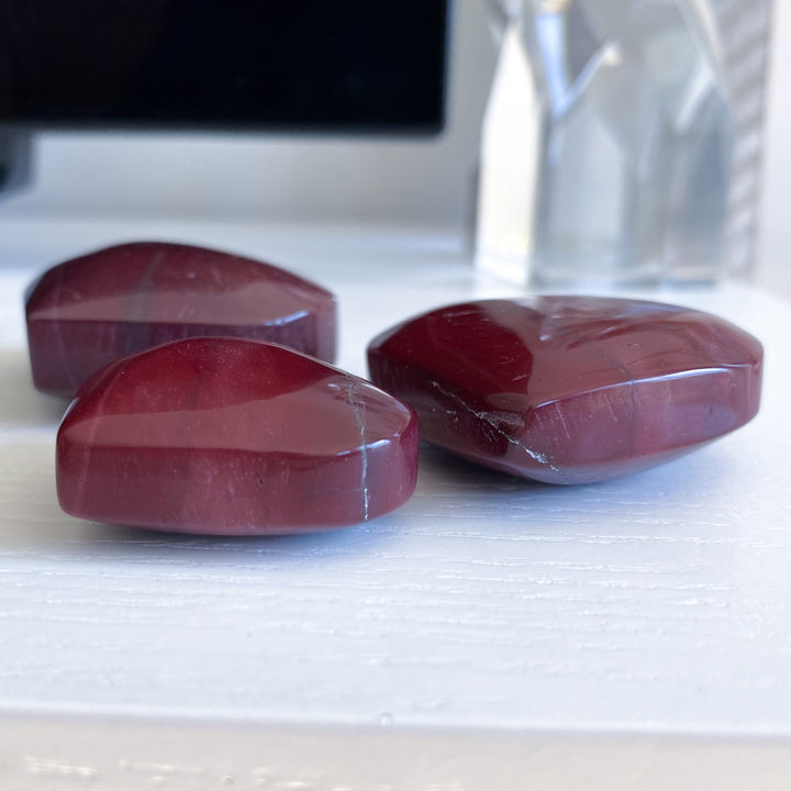 Three red stones on a white surface with a blurred background