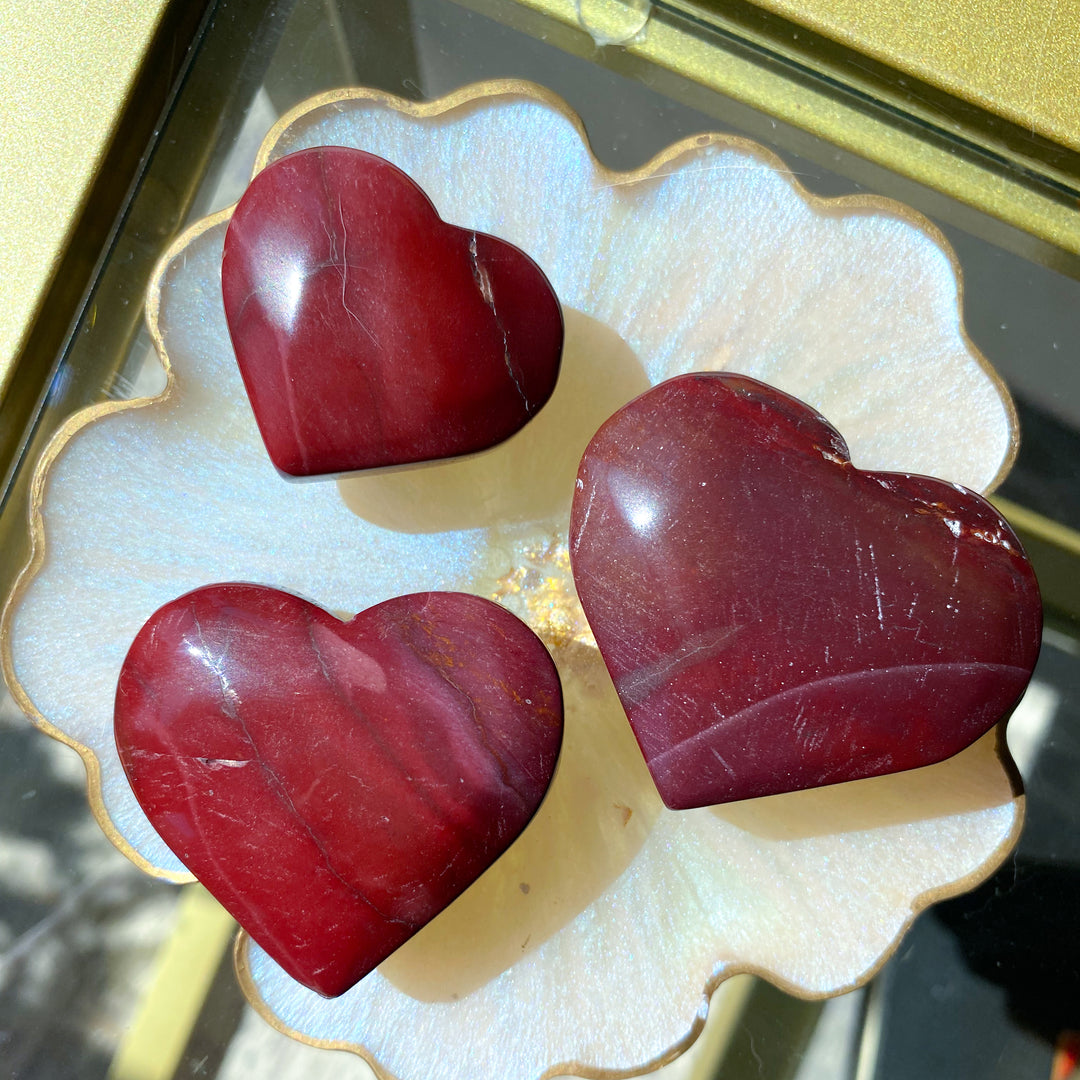 Three red heart-shaped objects on a decorative white surface with gold trim.