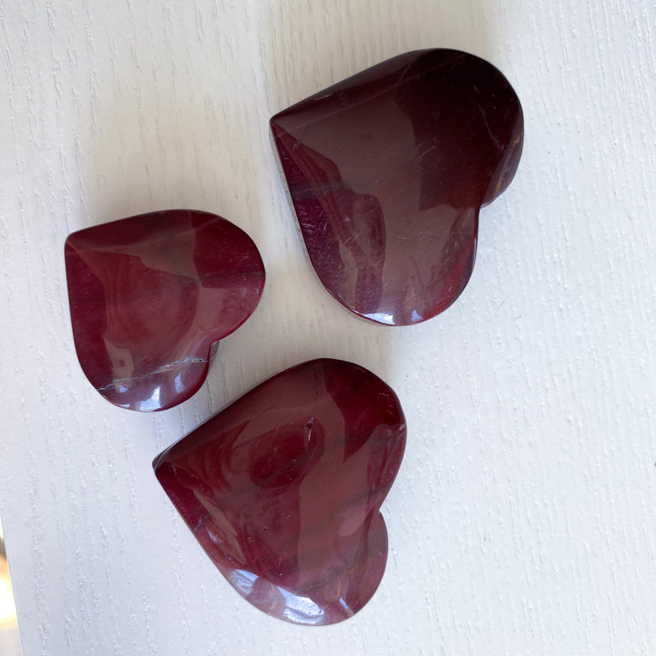Three polished red stones on a white surface