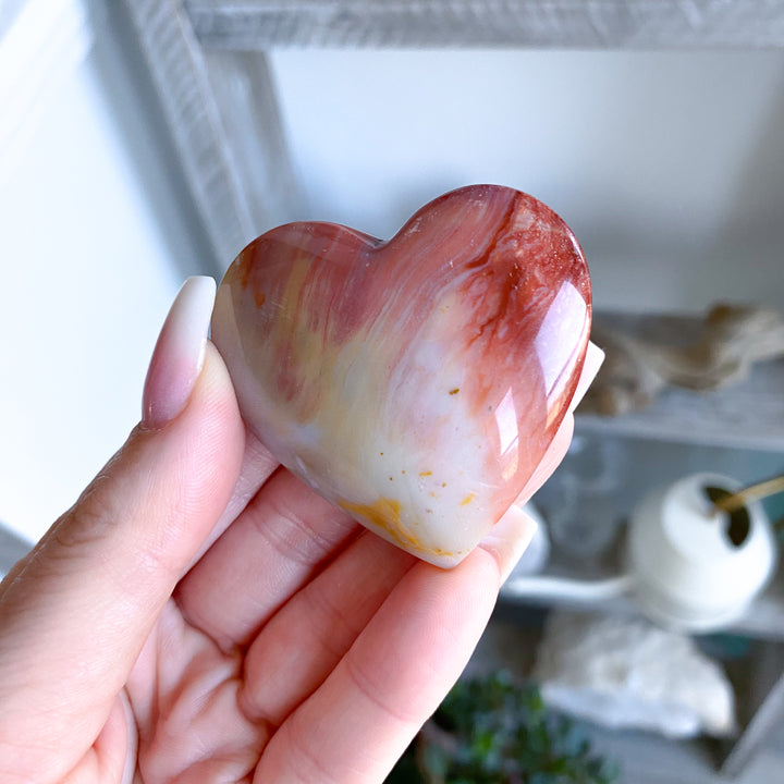 Heart-shaped stone held in a hand with a blurred background
