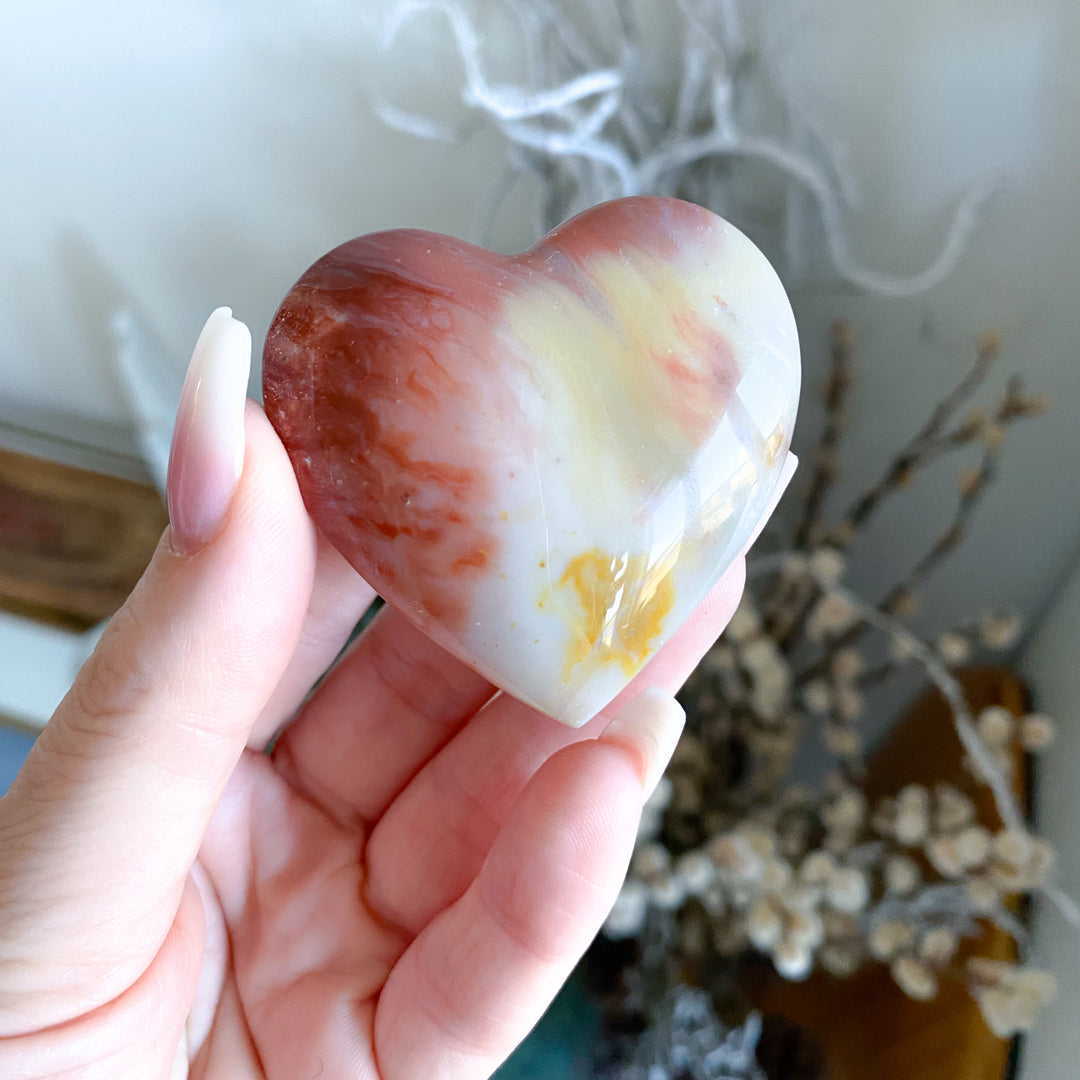 Heart-shaped stone held in a hand with a blurred background