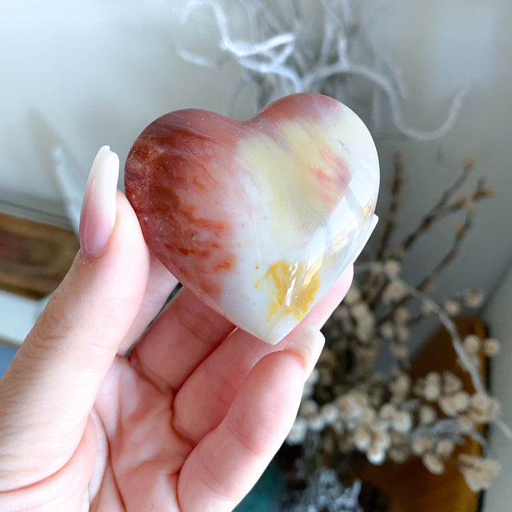 Heart-shaped stone held in a hand with a blurred background