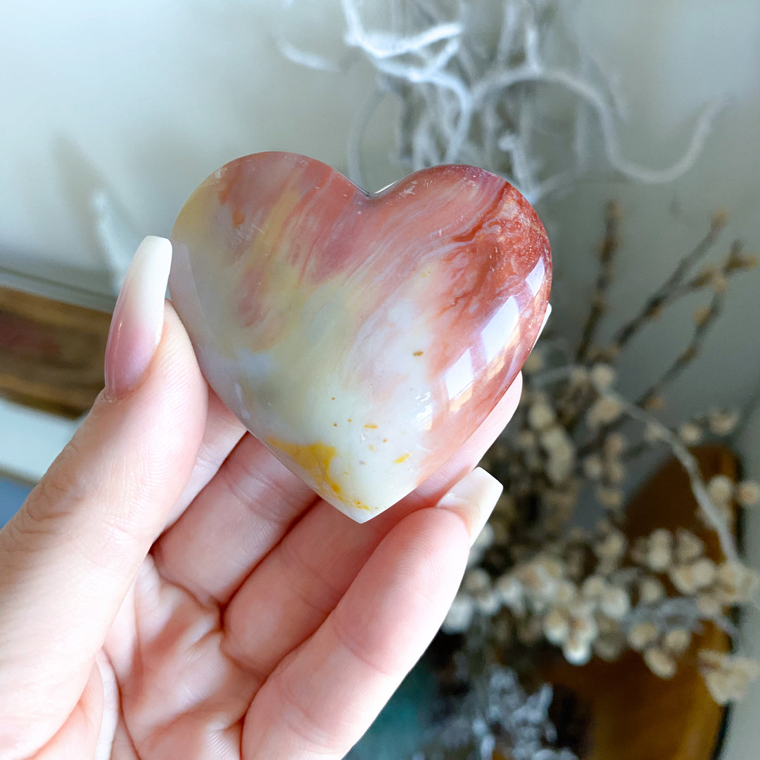 Heart-shaped soap held in a hand with a blurred background