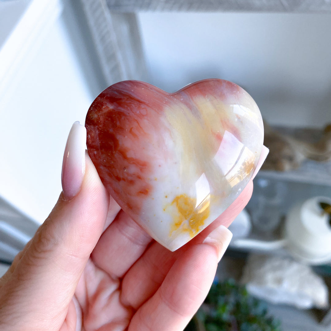 Heart-shaped stone held in a hand with a blurred background