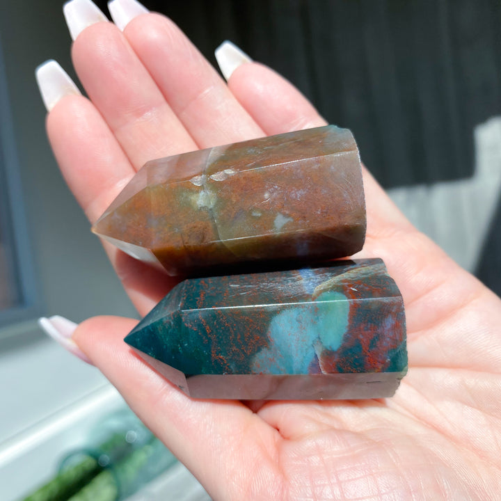 Hand holding two multicolored stone crystals with a blurred background