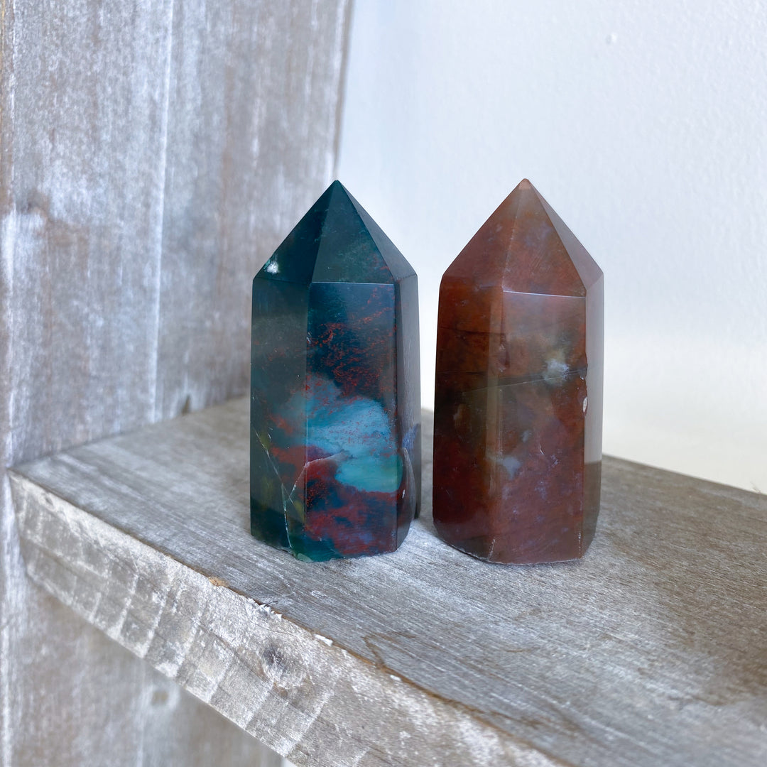 Two crystal towers on a wooden surface with a neutral background