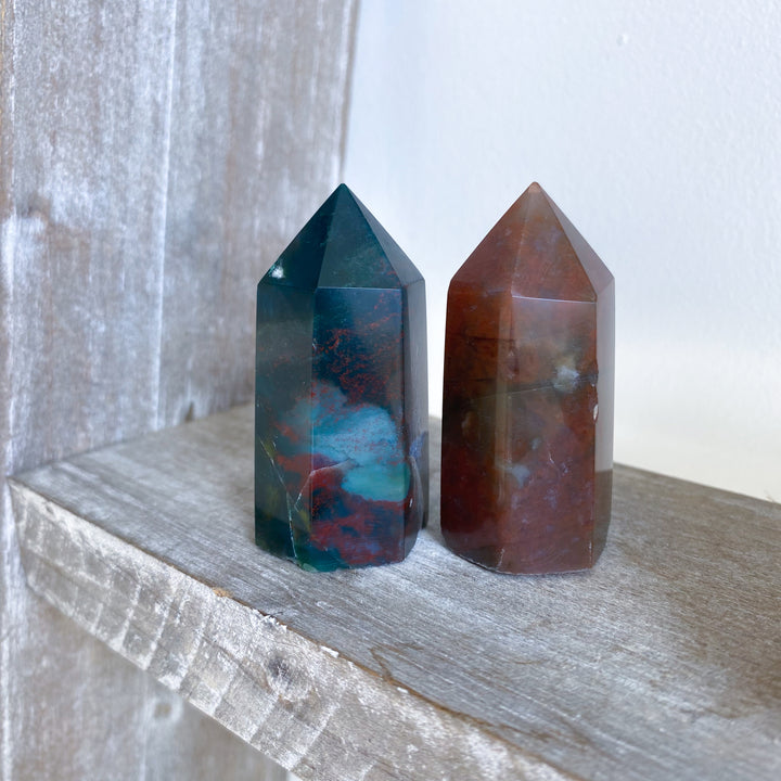 Two crystal towers on a wooden surface with a neutral background