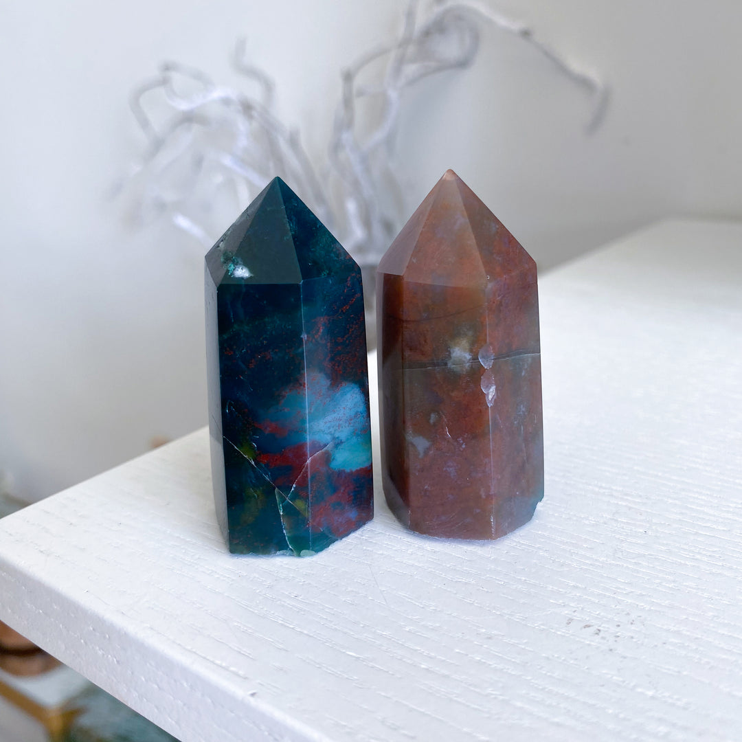 Two crystal towers, one blue and one brown, on a white surface with a blurred background.