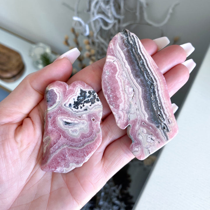 Hand holding two pink and gray agate stones with a blurred background