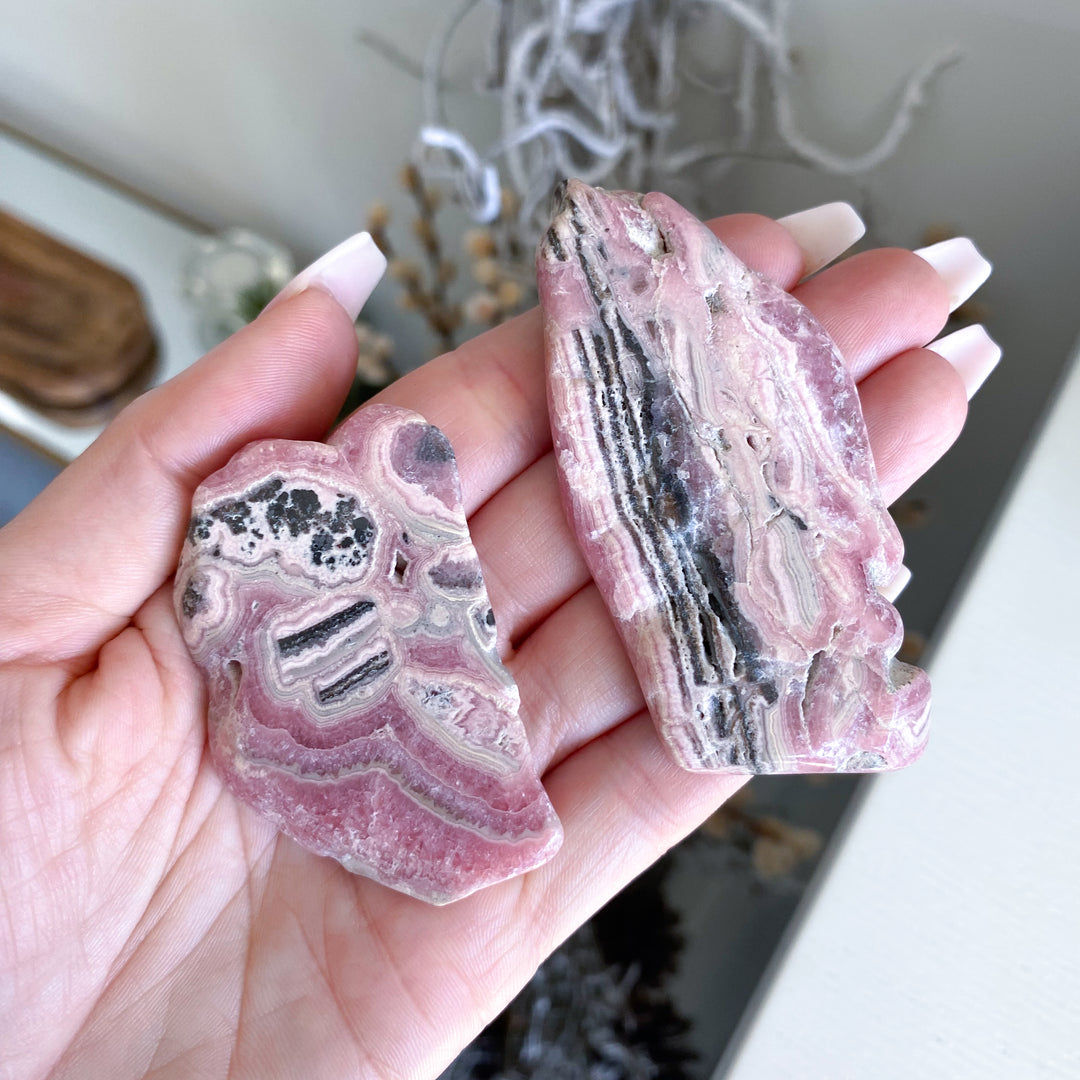 Hand holding two pink and gray crystal rocks with a blurred background
