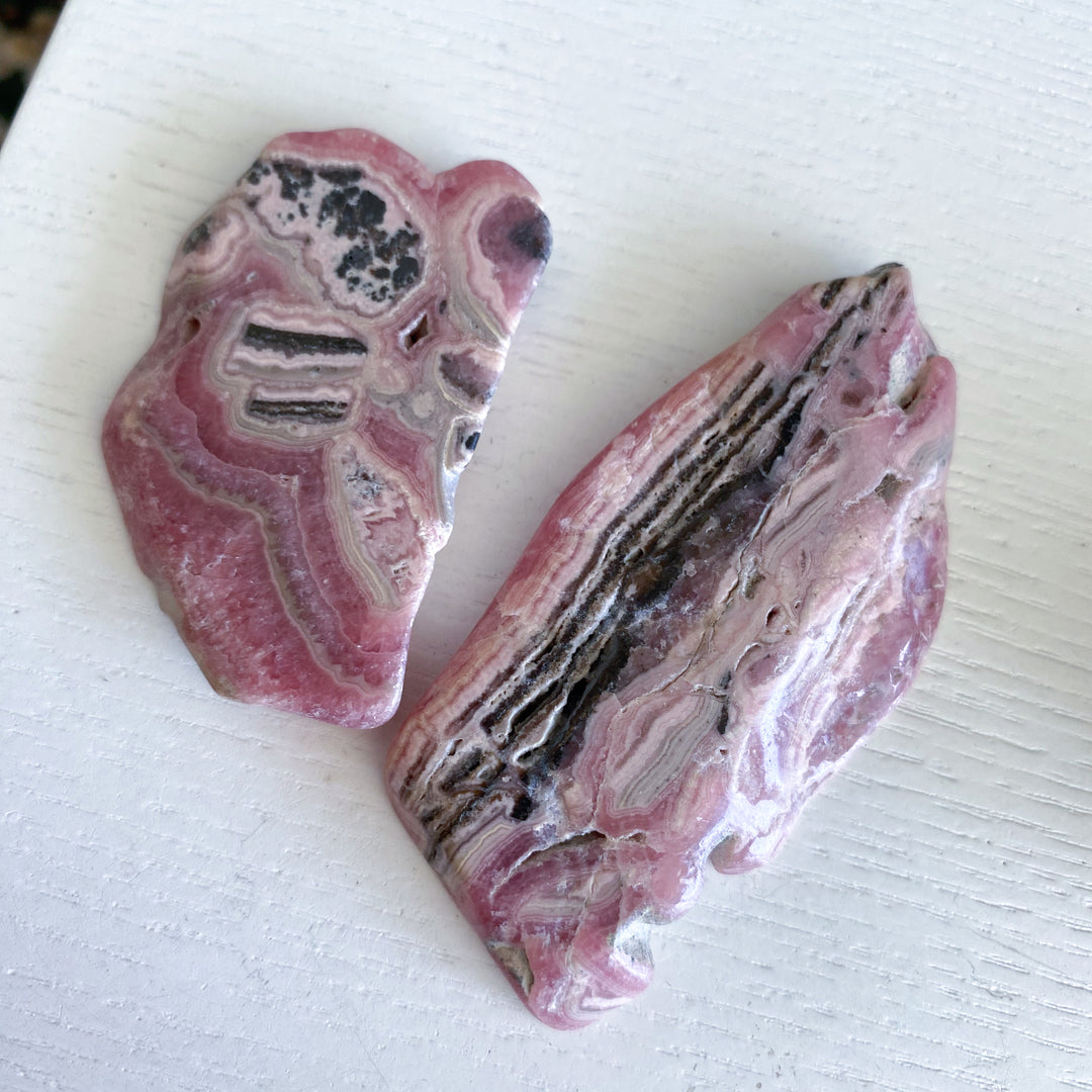 Two pink and black patterned stones on a white surface