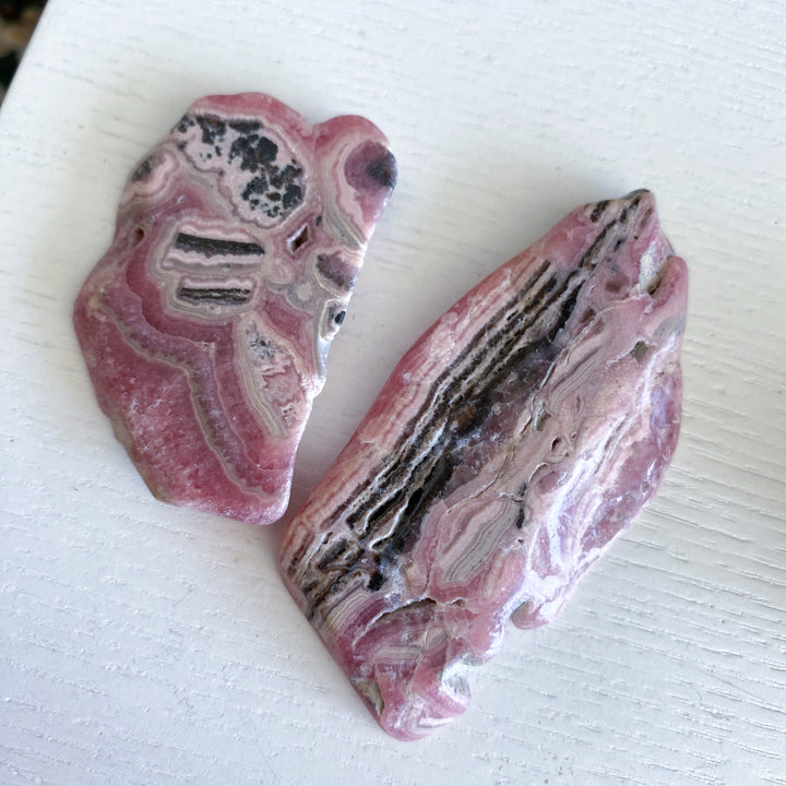 Two pink and black patterned stones on a white surface