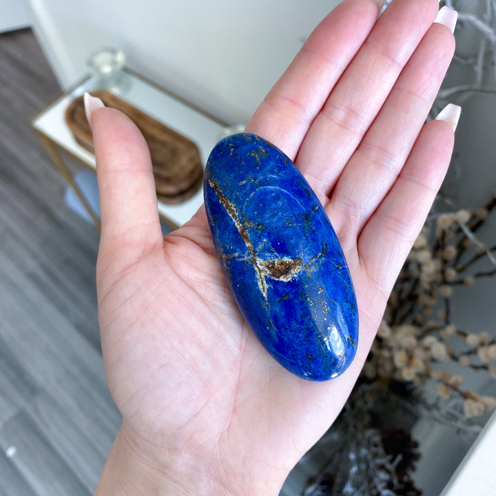 Hand holding a blue stone with a blurred indoor background