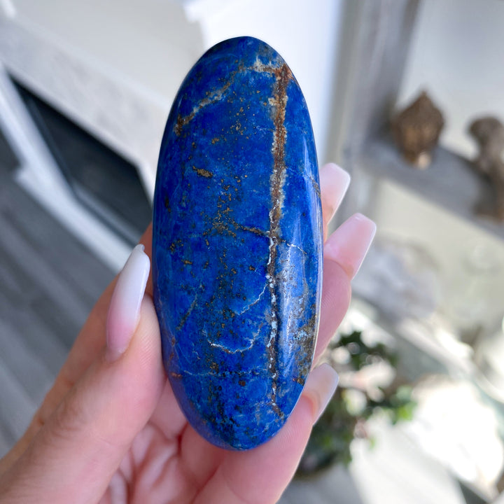 Hand holding a blue stone with a blurred background