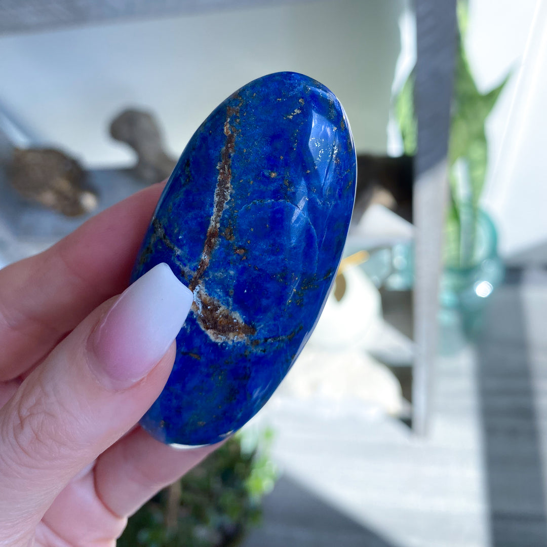 Hand holding a blue stone with a blurred indoor background