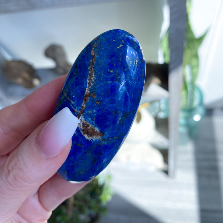 Hand holding a blue stone with a blurred indoor background