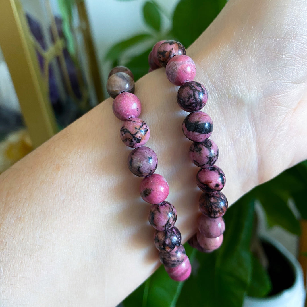 Pink and brown beaded bracelet on a wrist with a blurred background