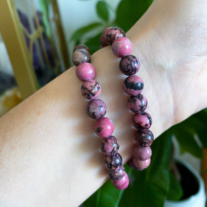 Pink and brown beaded bracelet on a wrist with a blurred background