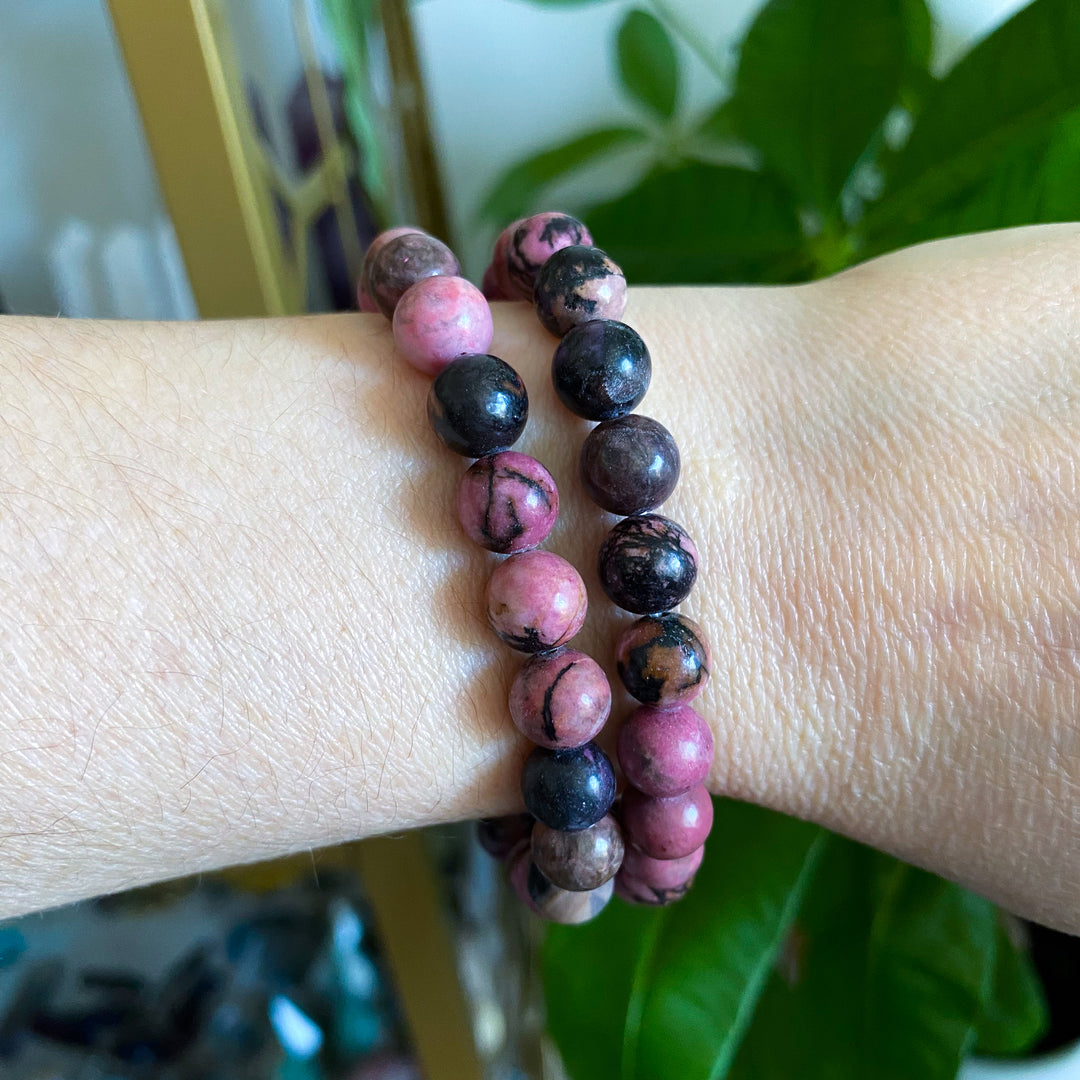 Two beaded bracelets on a wrist with a blurred background