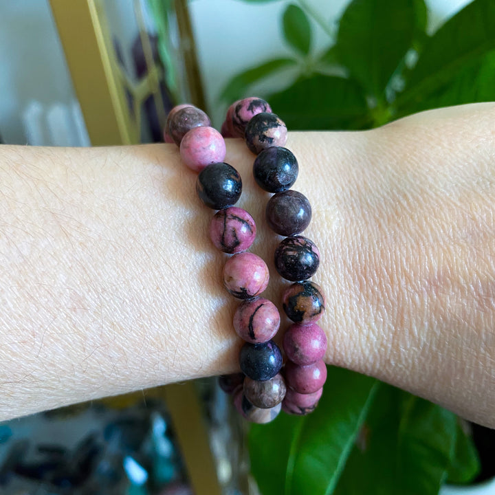 Two beaded bracelets on a wrist with a blurred background
