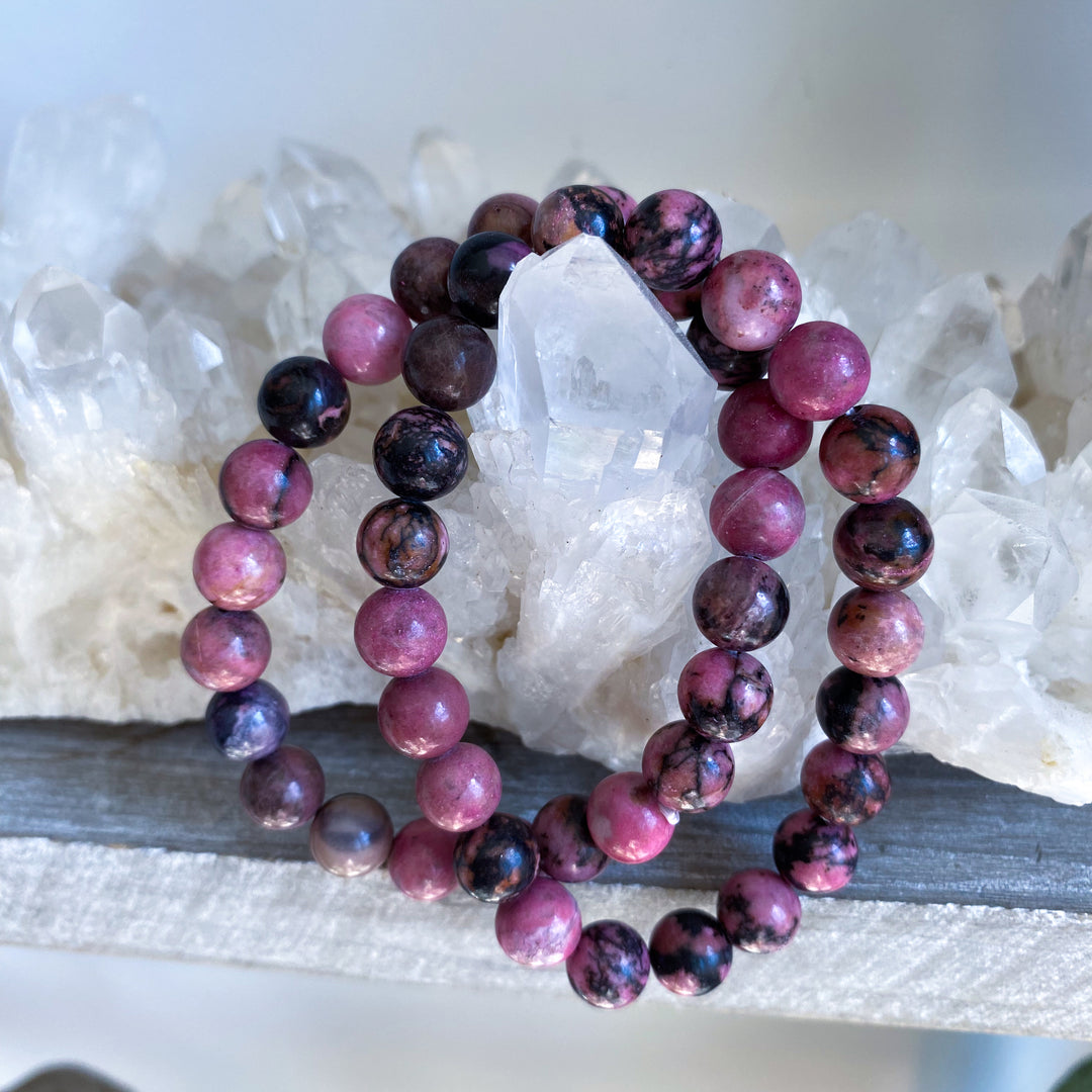 Stack of pink and purple beaded bracelets on a white crystal background