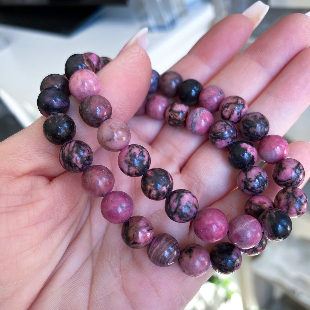 Hand holding a bracelet with purple and black marbled beads.