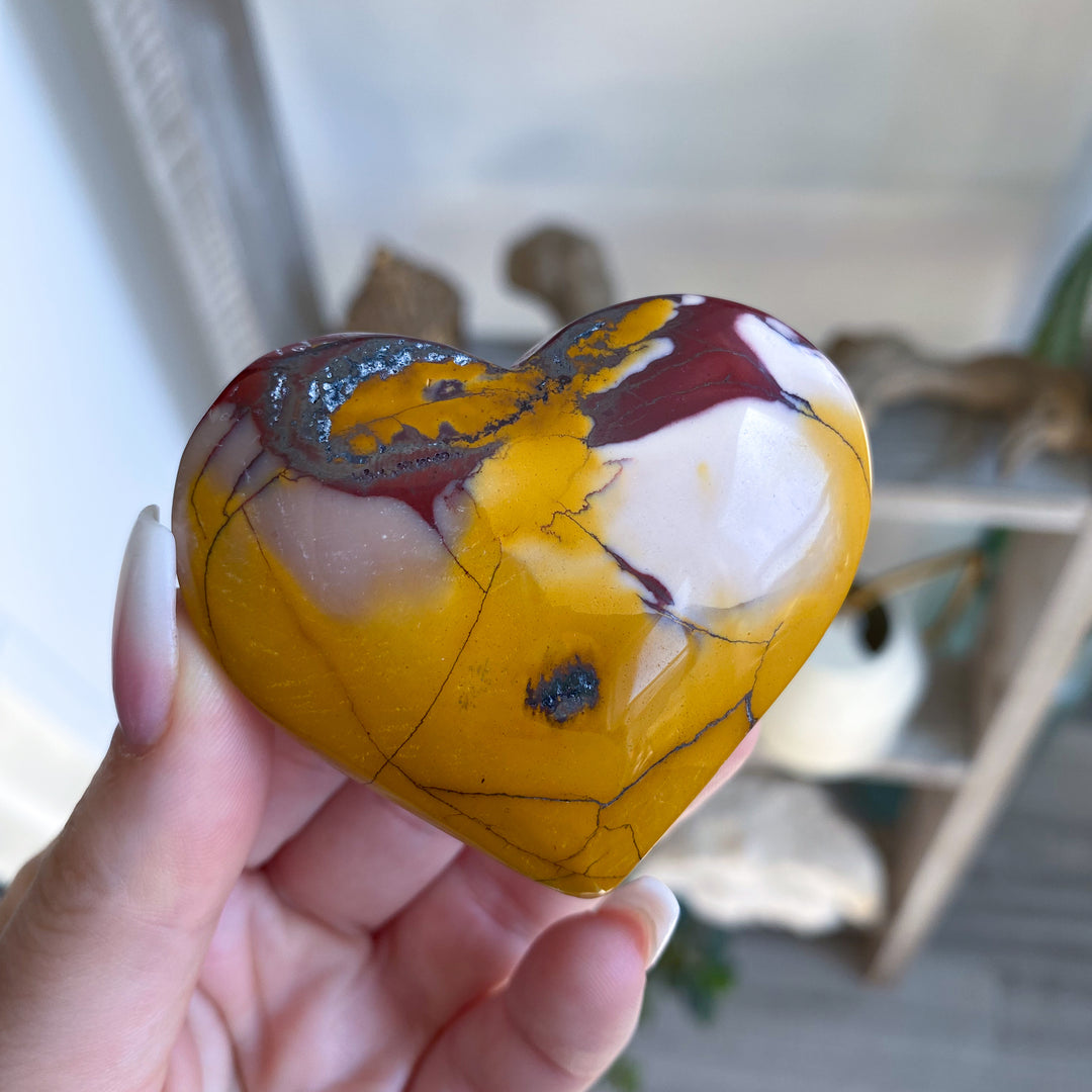 Heart-shaped marbled stone held in a hand with a blurred indoor background